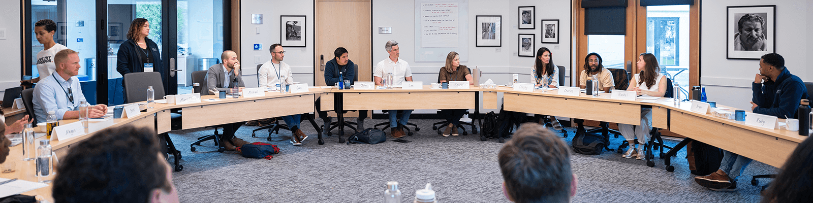 a large conference room filled with professionals sitting at tables situated in a circle